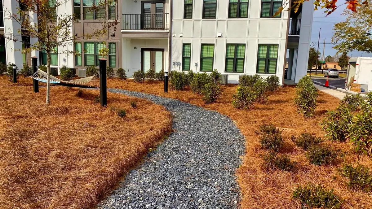 Faded golden straw beds along a gravel path, ready for a fresh top layer